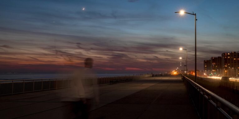 An edited photo showcasing streetlights alongside a boardwalk