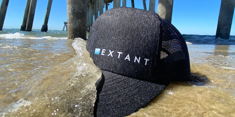 An Extant branded hat being washed by ocean waves